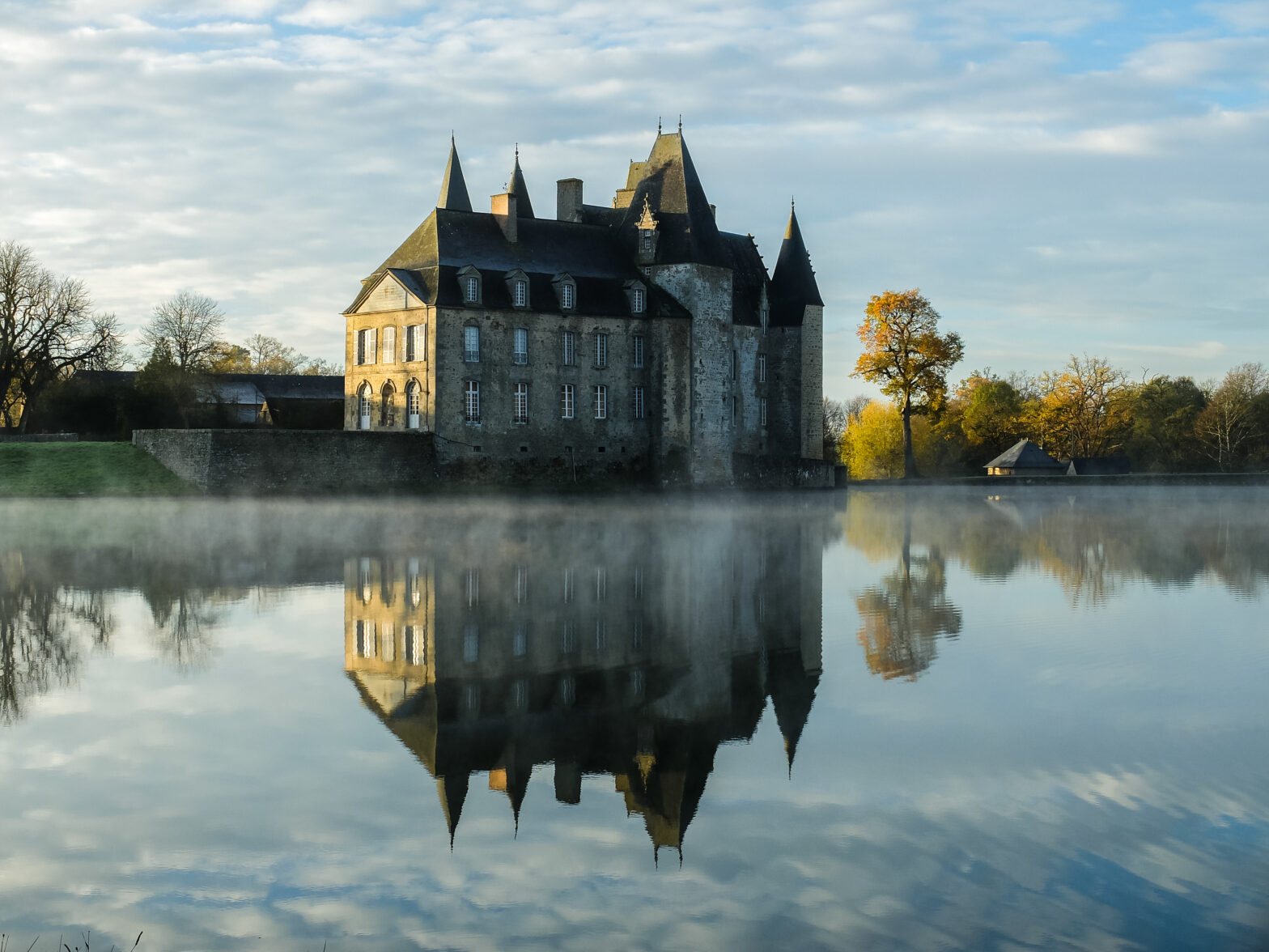 Clear lake with the reflection of a huge castle against the cloudy sky in autumn